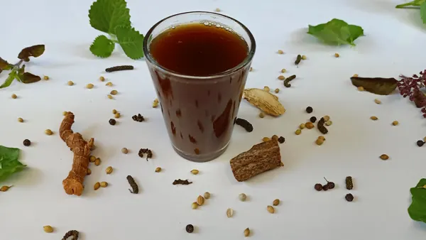 A glass of sukku malli (dry ginger and coriander) coffee with whole spices