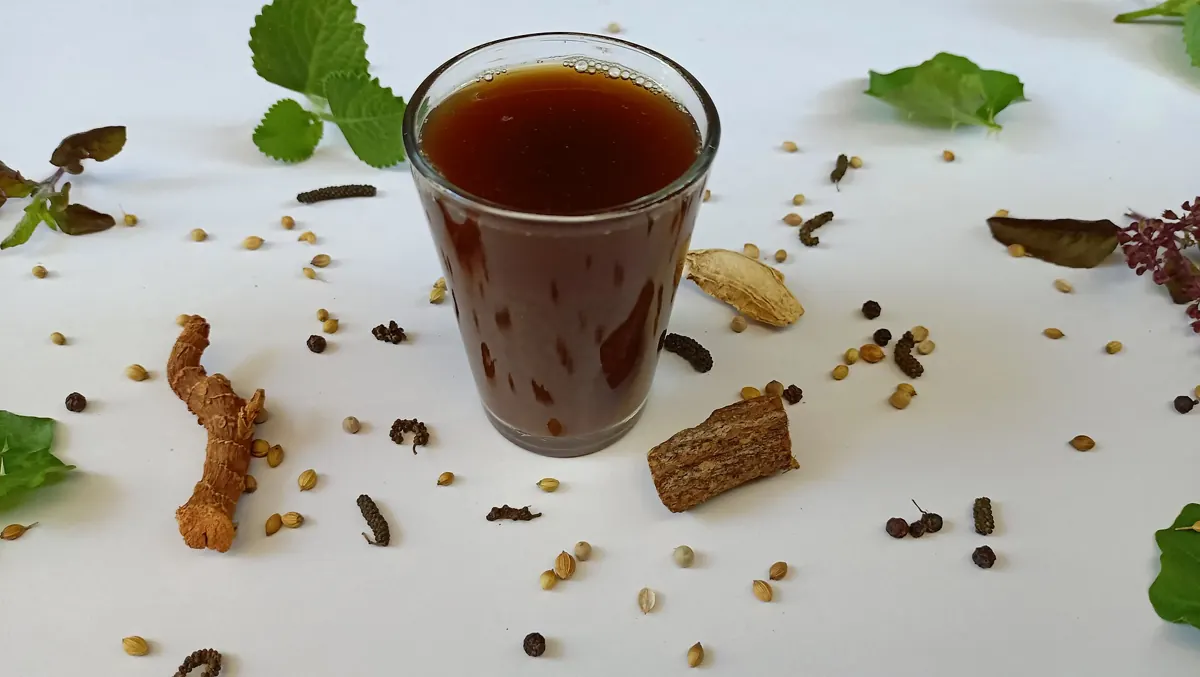 A glass of sukku malli (dry ginger and coriander) coffee with whole spices